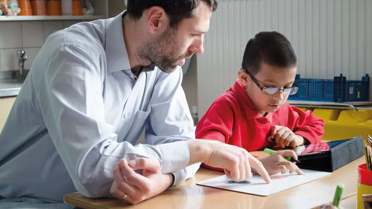 teacher pointing at text assisting student