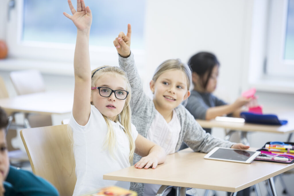 girls raising hands in classroom