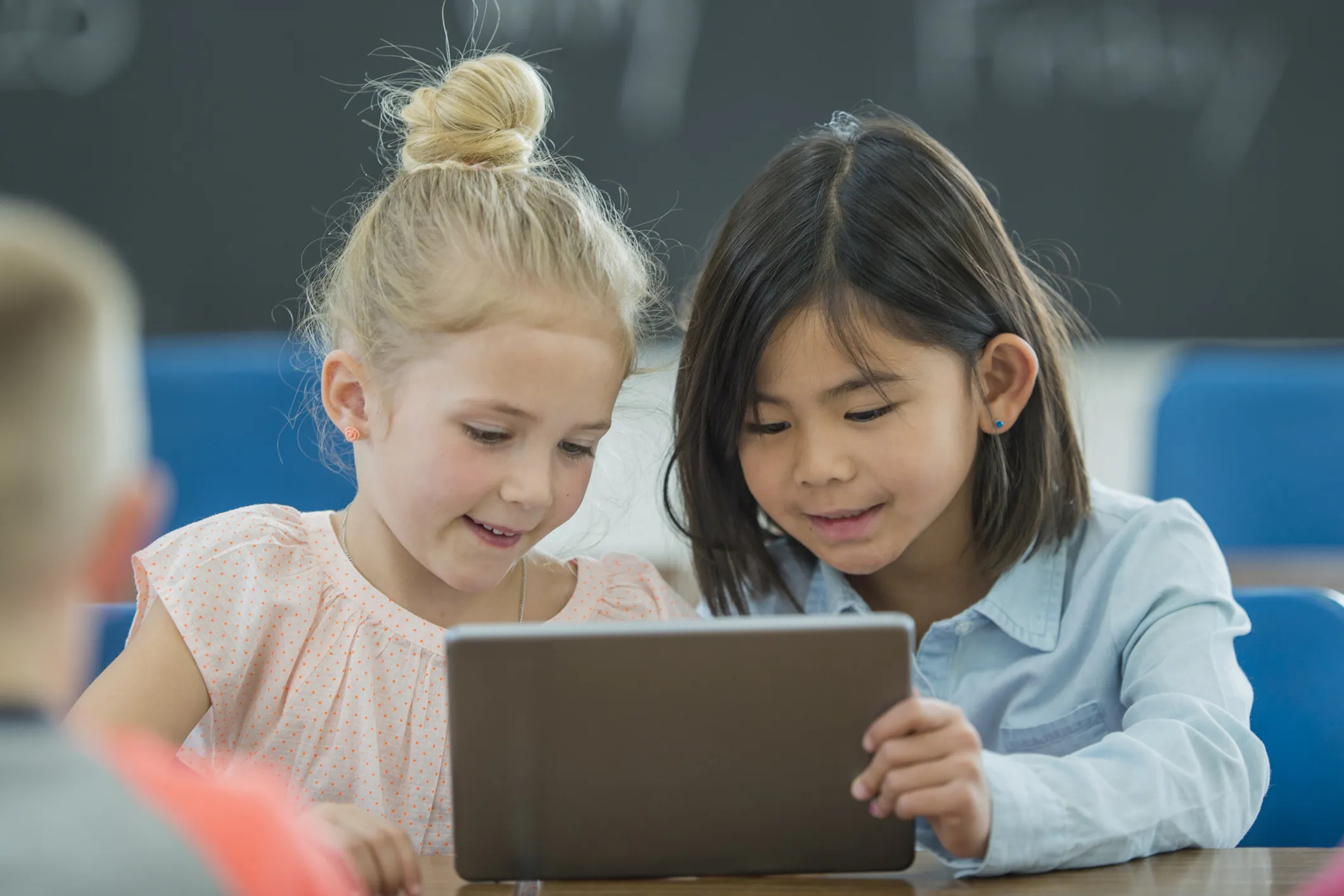 two young girls reading on a tablet
