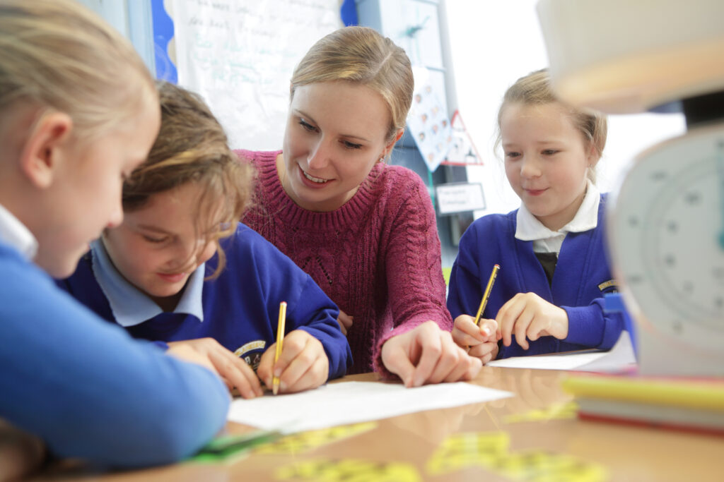 teacher helping students on assignments