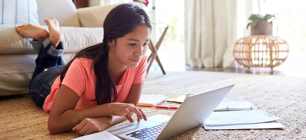 student laying on ground using laptop