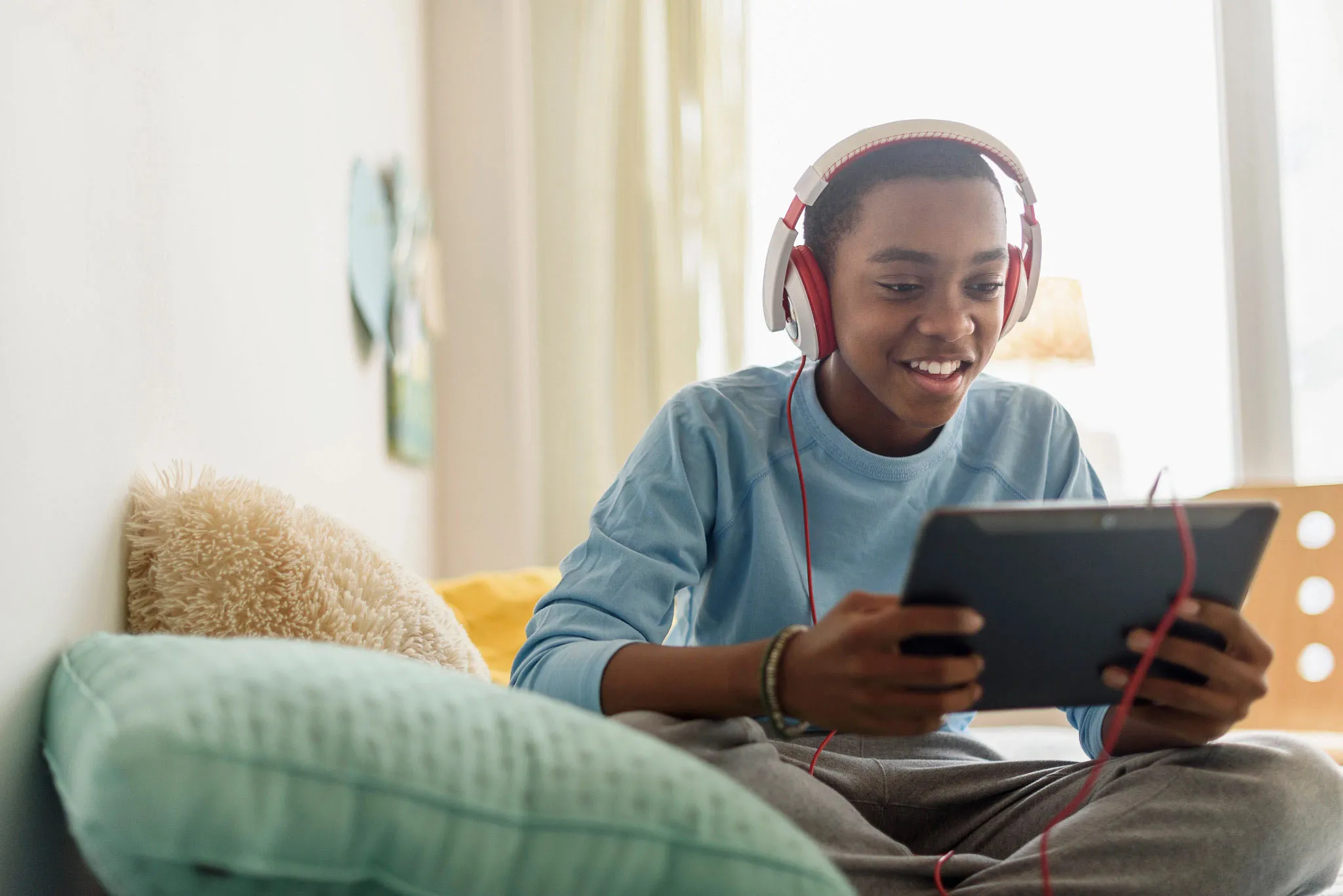A boy looking at his tablet while wearing headphones