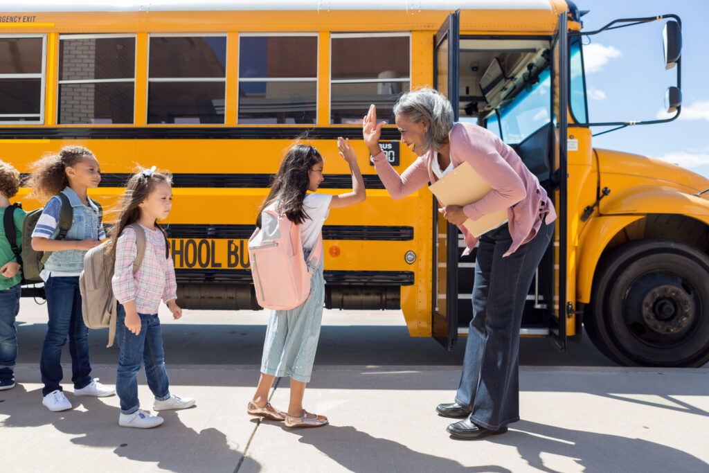 teacher with students at school bus 