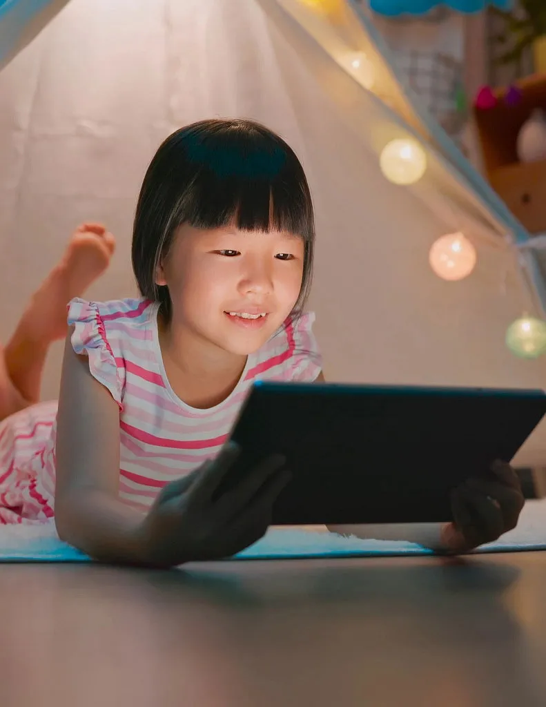 young student laying down on tablet