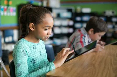girl using tablet next to boy