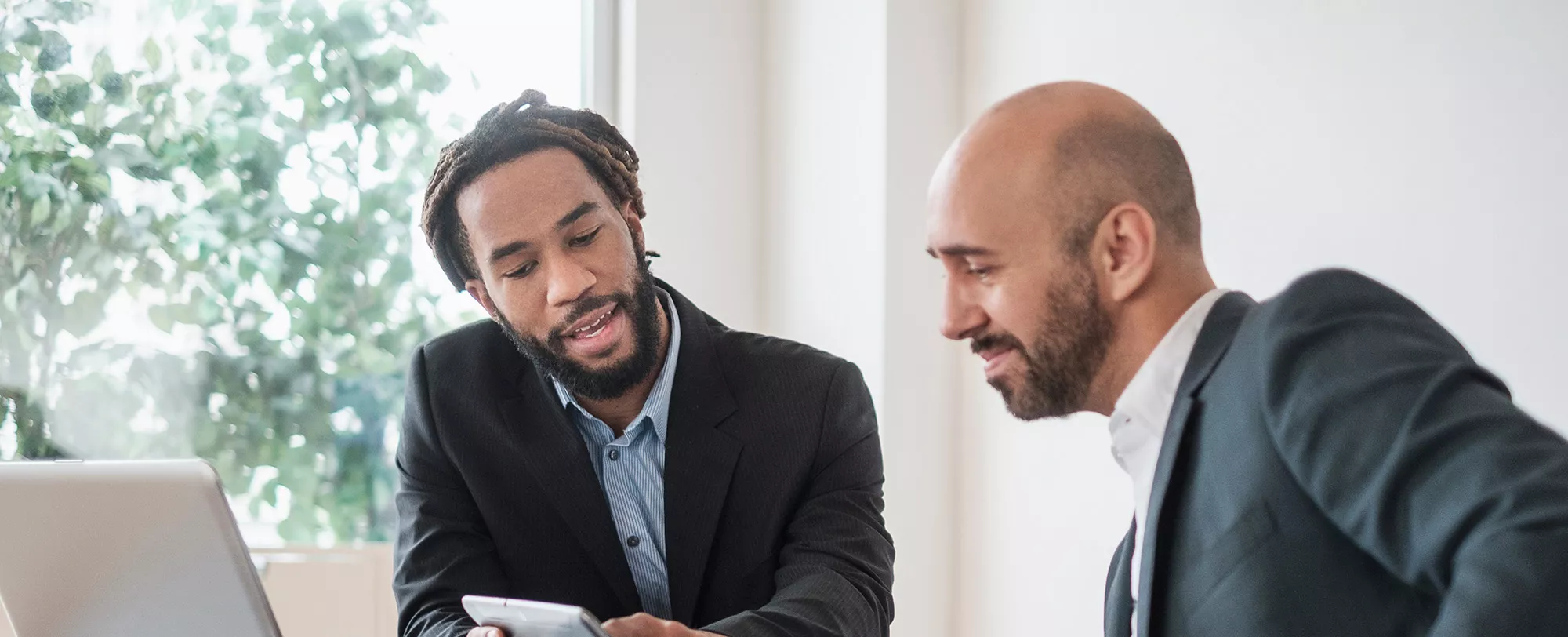 two suited men looking at a phone
