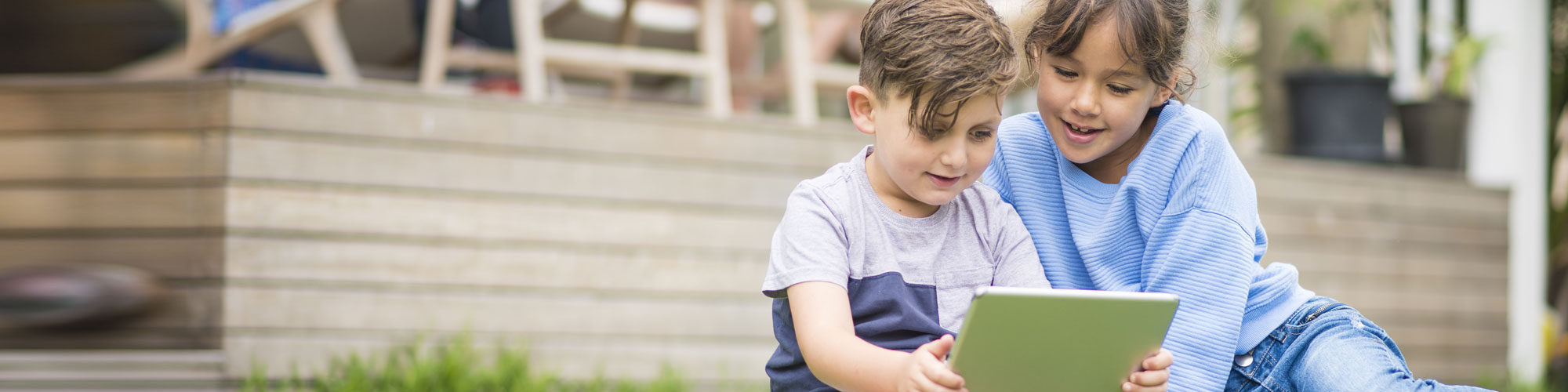 2 kids reading on a lawn