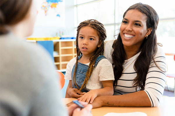 Little girl sitting on her mom's lap in a classroom