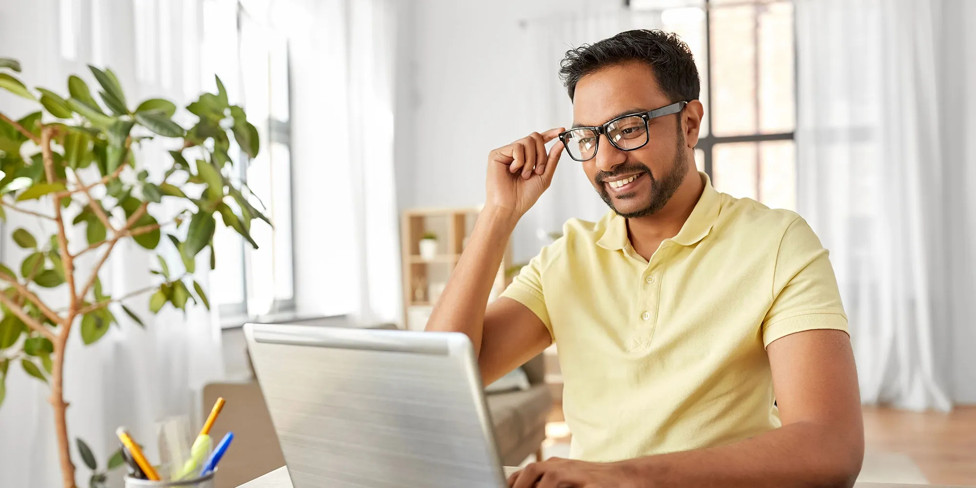 man adjusting glasses using laptop