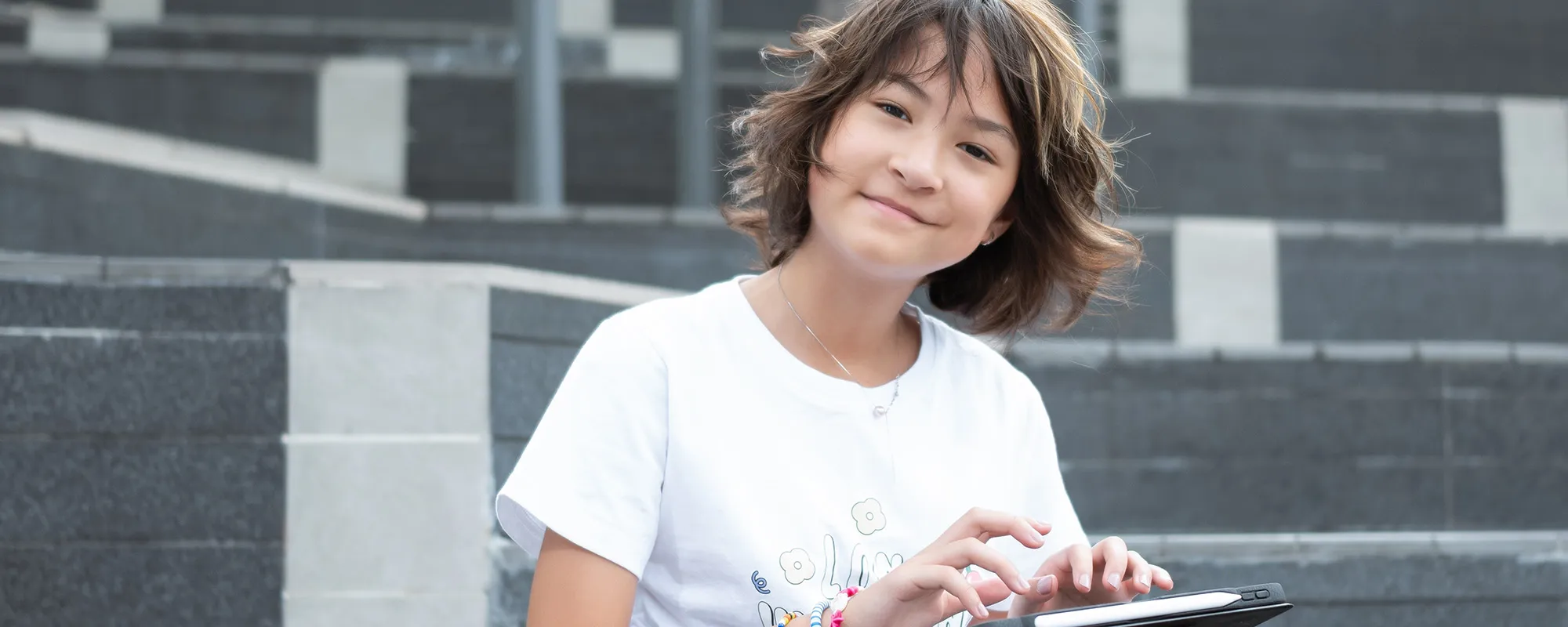 Girl outside her school with a tablet computer