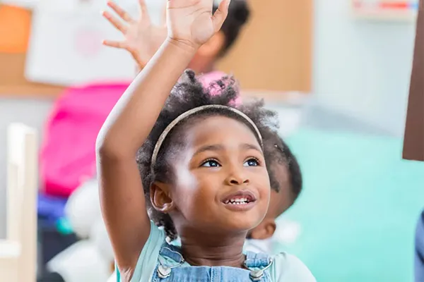 Girl with her hand raised in class