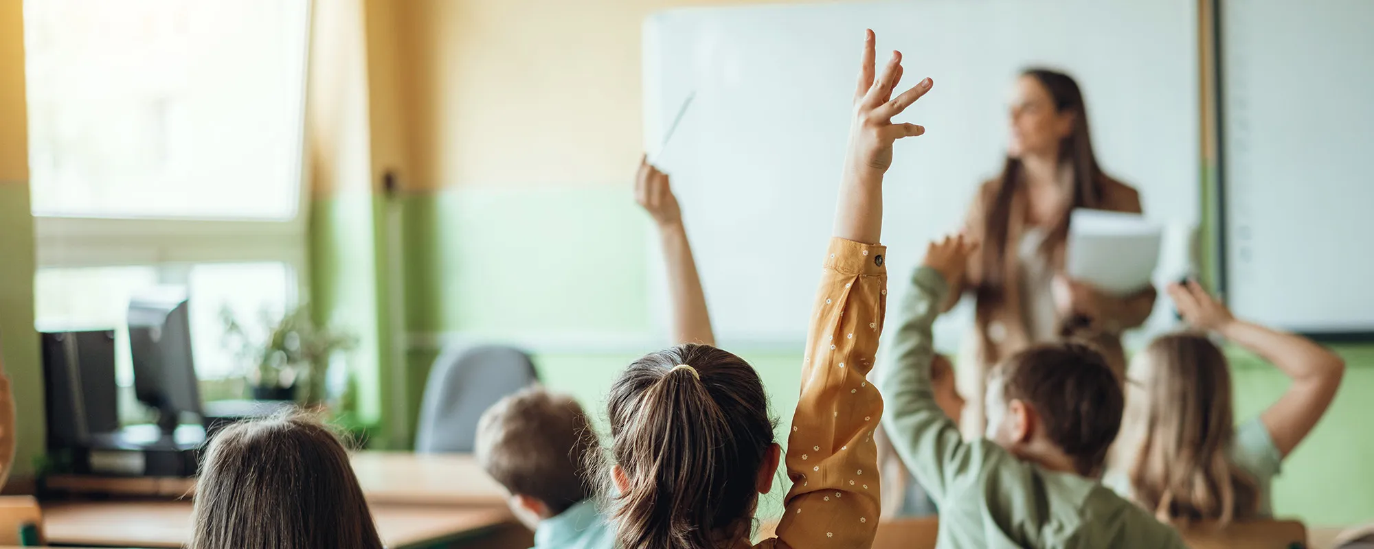 Students raising their hands in a classroom