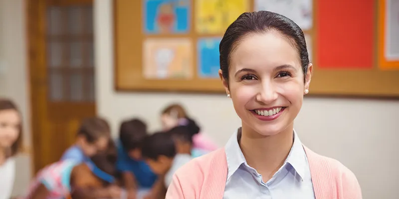 A smiling teacher in a primary school classroom
