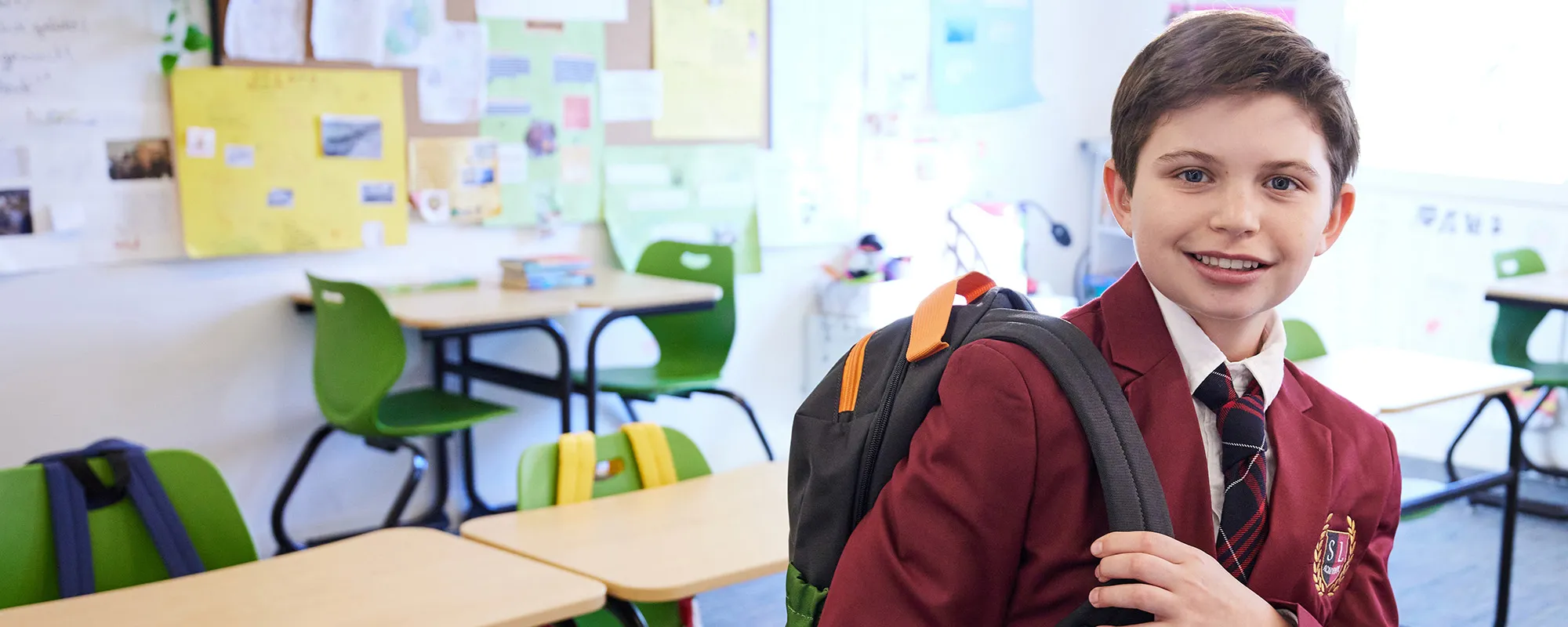 uniformed student with a backpack in a classroom