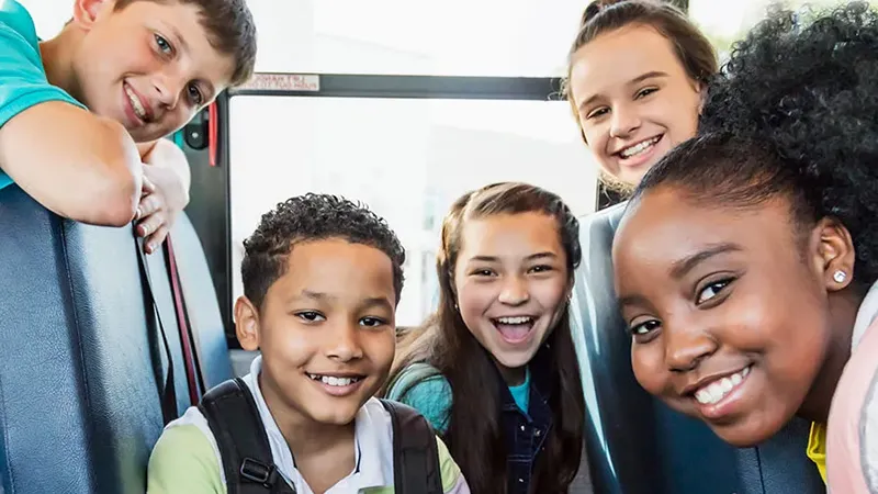 Middle school students on a bus smiling and socializing