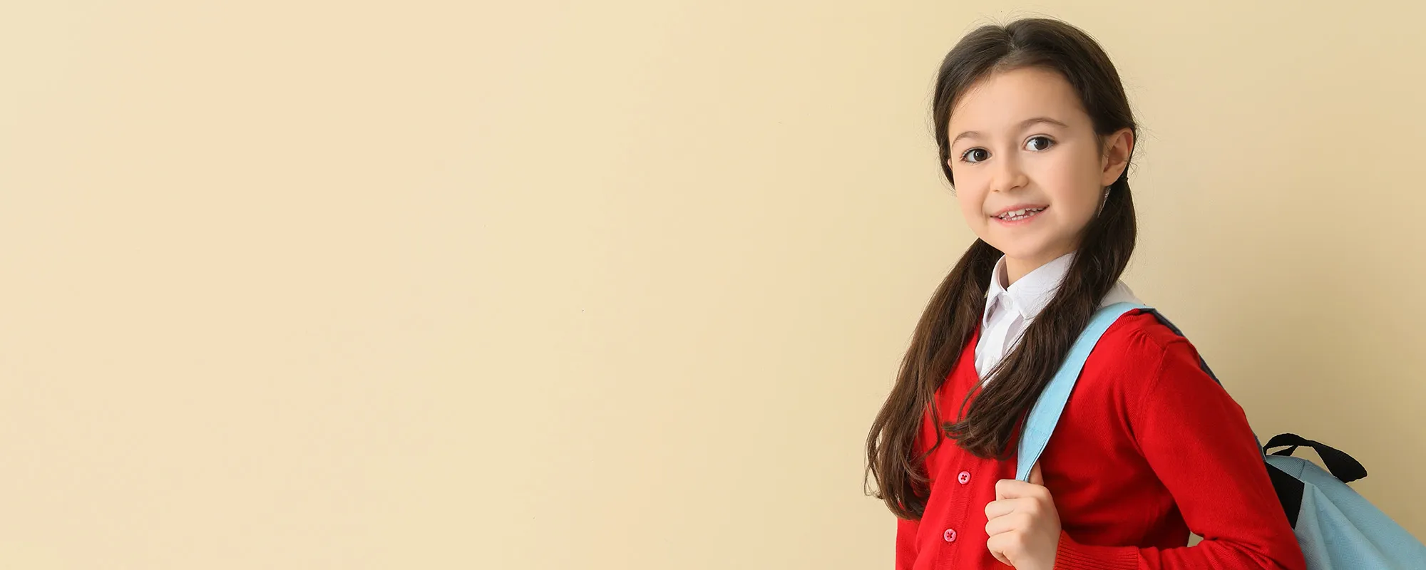 an image of a girl student with a backpack wearing a red uniform