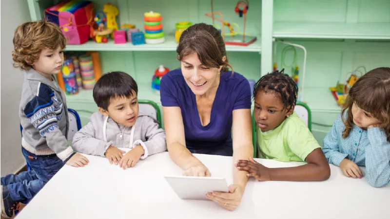 a teacher at a table surrounded by preschool students